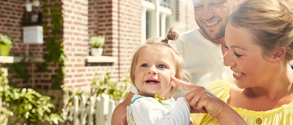 Haus- und Grundbesitzer-Haftpflicht Junge Familie mit Kind vor ihrem Haus