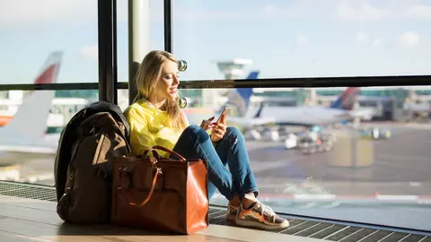 Junge Frau mit Reiserücktrittsversicherung und Gepäck am Flughafen