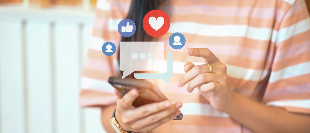 Handy in der Hand mit Social-Media-Icons