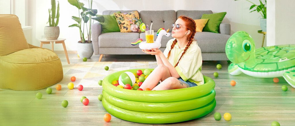 Mietkautionsversicherung Junge Frau mit Sonnenbrille und Drink im Planschbecken freut sich über die Vorteile der Mietkautionsversicherung