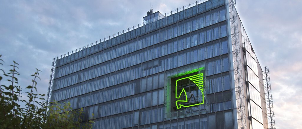 LVM-Gebäude mit LVM-Pferdelogo auf Fassade, umgeben von Fenstern, bewölkter Himmel