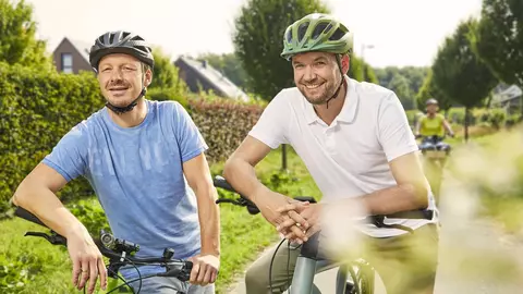 Zwei mittelalte Männer auf sommerlicher Radtour, im Gepäck die LVM-Fahrradversicherung für E-Bikes
