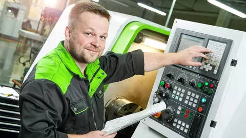 Facharbeiter vor großer Steuerungsmaschine. Das Unternehmen hat eine Maschinenversicherung.