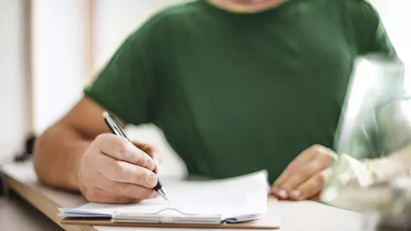 Student am Schreibtisch bearbeitet Unterlagen.