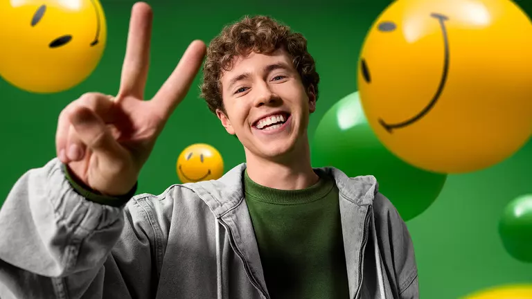 Ein junger Mann zeigt ein Peace-Zeichen umgeben von gelben Smileys.