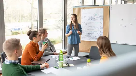Personen sitzen in einem Besprechungsraum und diskutieren an einem Flipchart