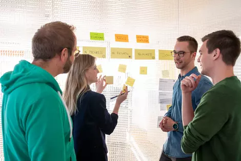 3 Personen stehen an einem Flipchart und diskutieren mit Post-Its