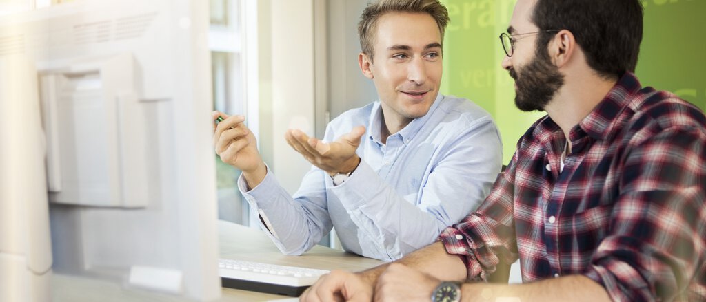 Versicherungsberater und Kunde schauen am Computer in die Beitragsrechnung