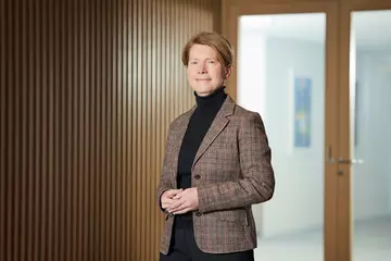 Sonja Kiefer steht vor einer Holzwand / Tür. 