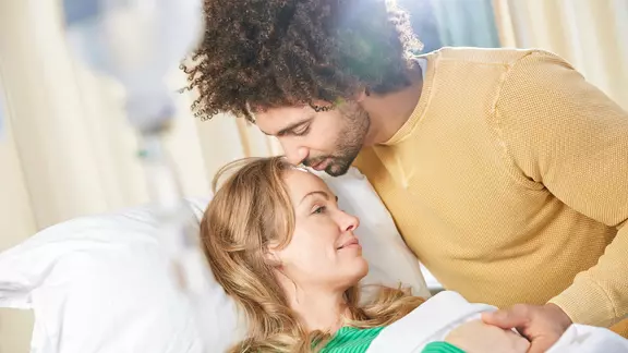 Frau im Krankenhaus bekommt Besuch von ihrem Mann