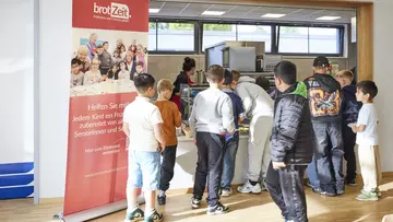 Eine Gruppe von Schülern steht an einer Essensausgabe in der Mensa ihrer Schule. Schülerinnen und Schüler nutzen das Frühstücksangebot in der Mensa der Norbertschule. Foto: LVM Versicherung/Bernd Schwabedissen