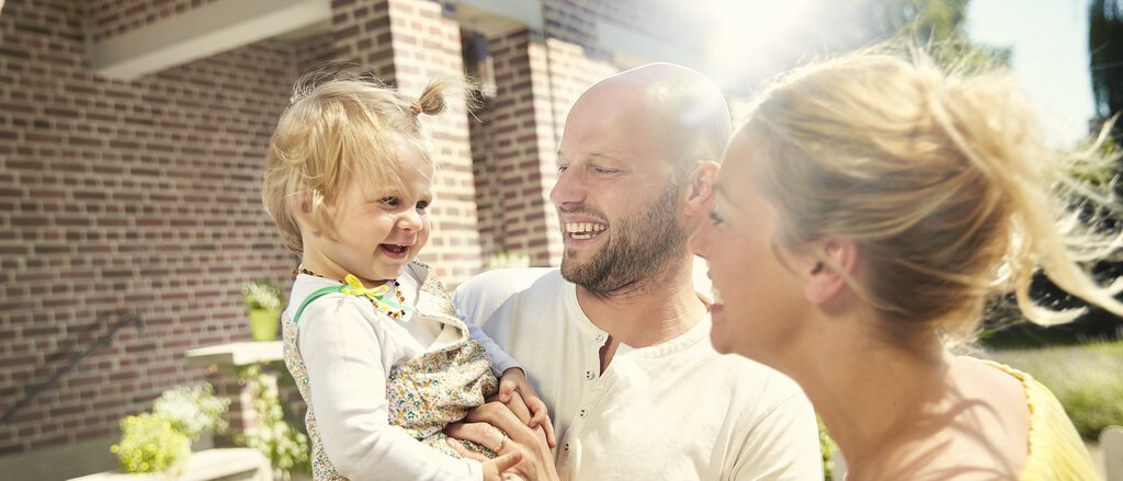 Immobilien-Rechtschutzversicherung Eine Familie steht sorgenfrei vor Ihrem Haus dank der Immobilien-Rechtsschutzversicherung.