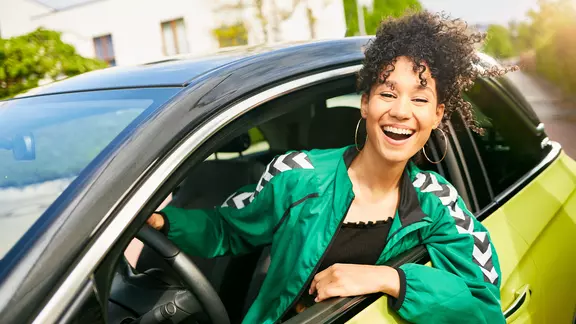 Junge Frau in ihrem ersten Auto.