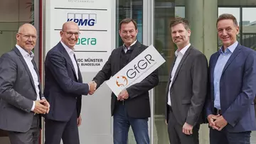 Vertreter der LVM Versicherung und der GfGR halten ein Unternehmensschild in die Kamera. 