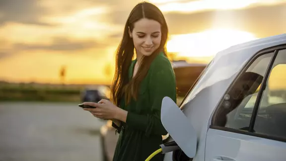 Eine junge Frau lädt ihr E-Auto.
