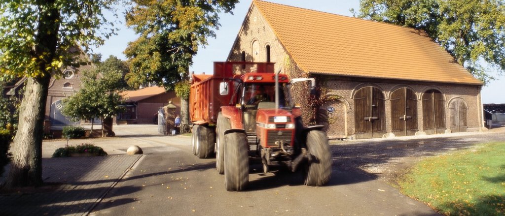 Landwirt fährt mit seinem Trecker und Anhänger vom Hof