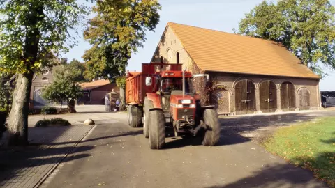 Landwirt mit Traktor vor Hofanlage