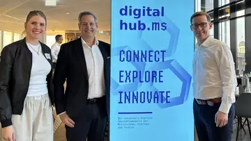Drei Personen stehen vor einem Banner, auf dem Connect, Explore und Innovate steht. V.l.: Francis Möllerwessel, Vorständin, Digital Hub münsterLand, Markus Loskant, IT-Vorstand LVM Versicherung und Sven Grave, Vorstand DigitalHub münsterLand.