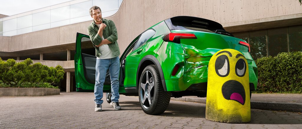 Mann steht vor seinem verbeulten Auto