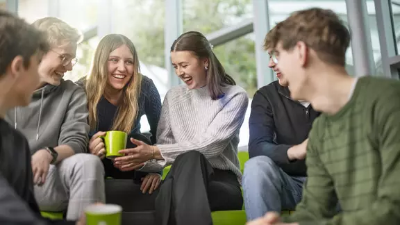 Sechs LVM-Azubis trinken Kaffee und lachen zusammen.