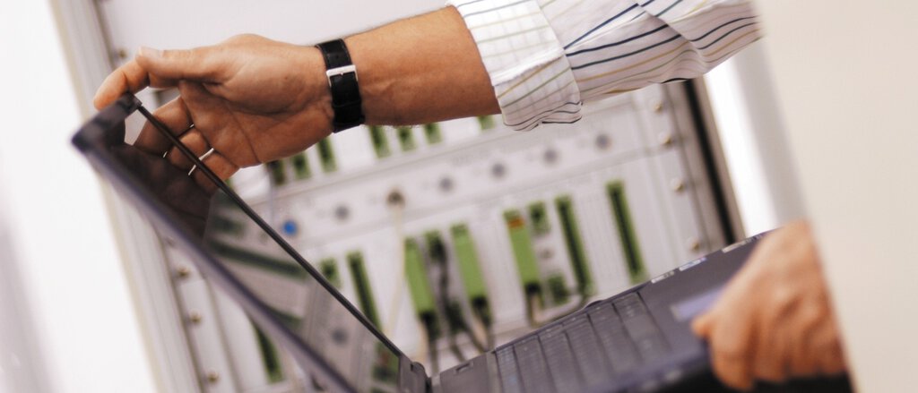 Mann mit Laptop vor Serverschrank